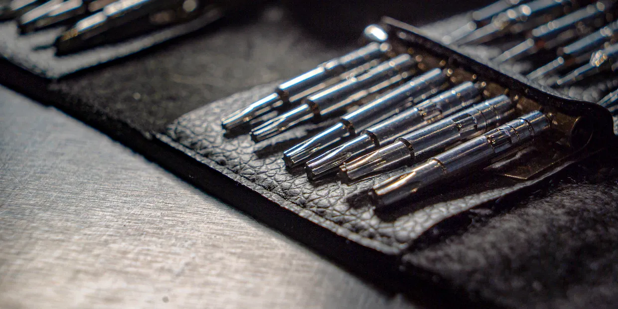 A multi-bit ratcheting screwdriver and an assortment of driver bits on a workbench