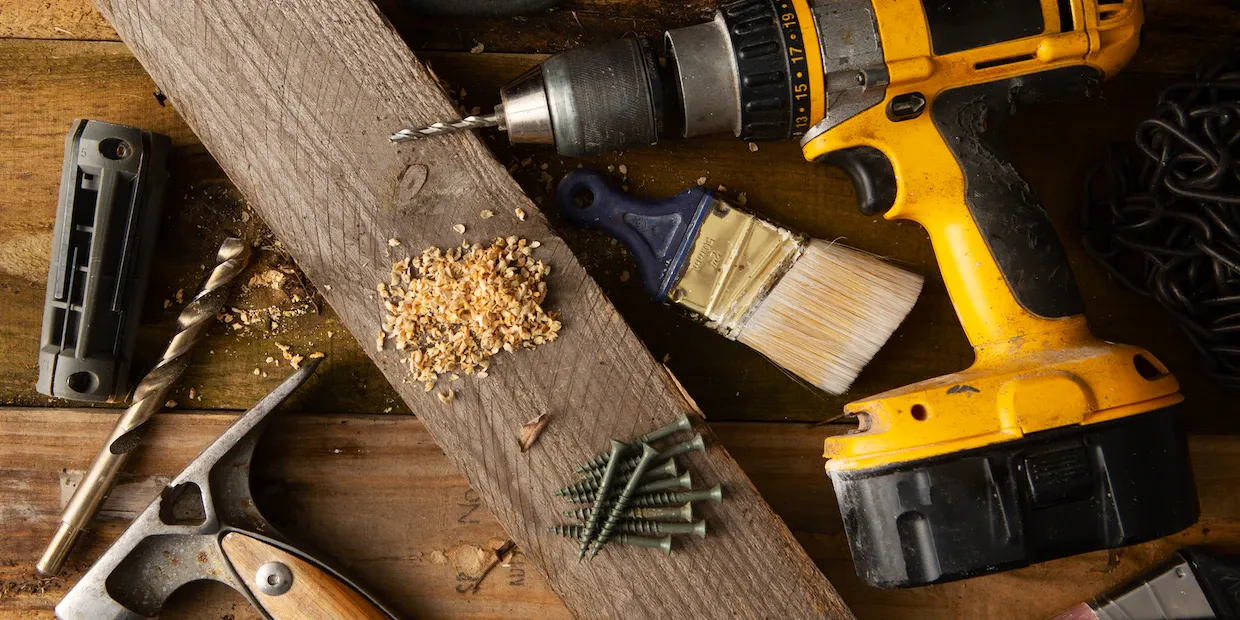 A cordless drill/driver resting on a workbench next to a set of bits